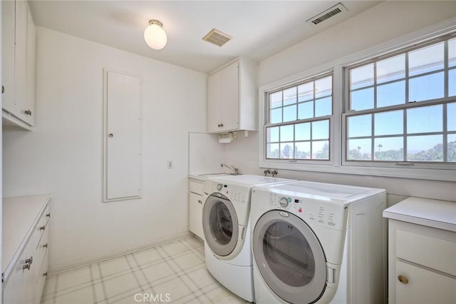 clothes washing area with cabinet space, visible vents, light floors, washing machine and dryer, and a sink