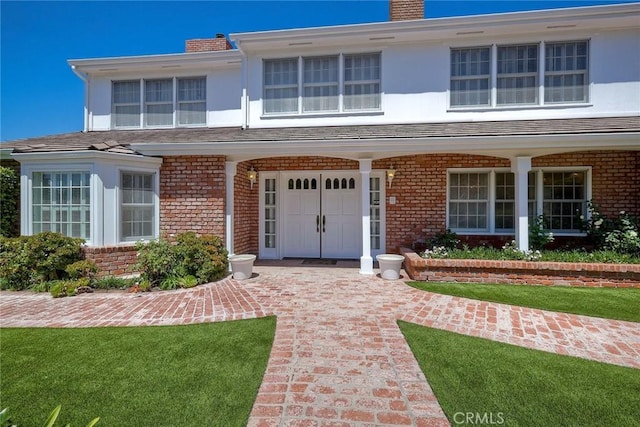 view of front facade featuring a chimney, a front lawn, and brick siding