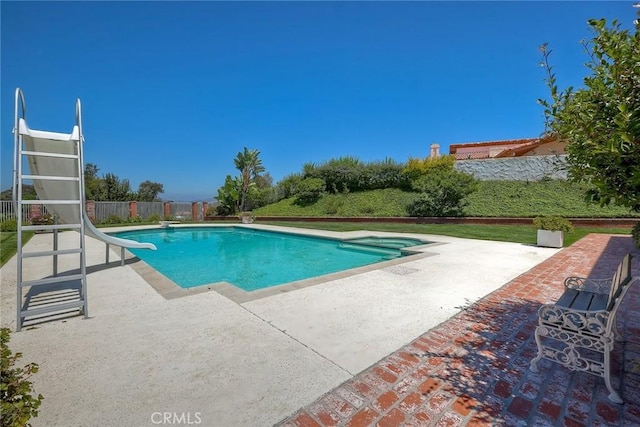 view of swimming pool featuring a water slide, fence, a diving board, a fenced in pool, and a patio area