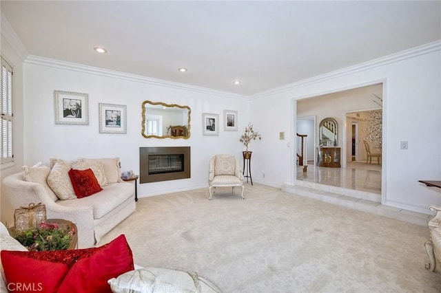 living area with crown molding, baseboards, a glass covered fireplace, and light colored carpet