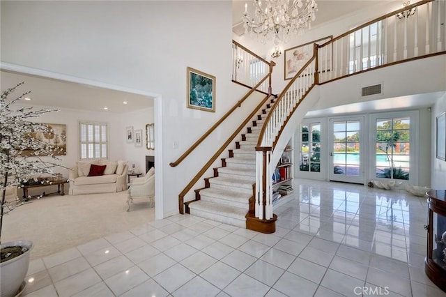 staircase featuring a high ceiling, visible vents, a chandelier, and crown molding