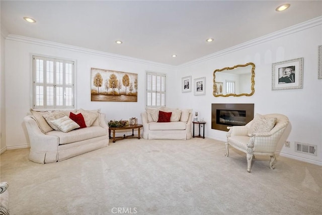 living room with carpet, crown molding, visible vents, a glass covered fireplace, and baseboards