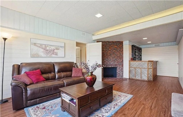 living room with wood-type flooring, a fireplace, and wood walls