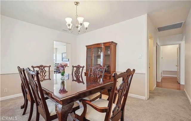 dining space with light colored carpet and a notable chandelier