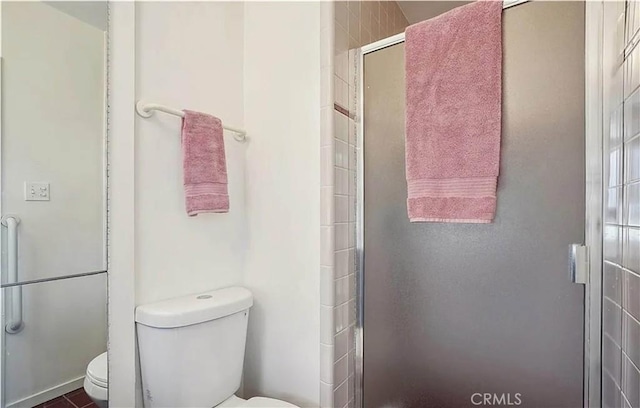 bathroom featuring toilet and a shower with door