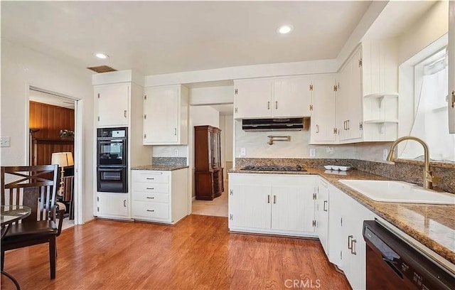 kitchen with black appliances, sink, white cabinetry, and range hood