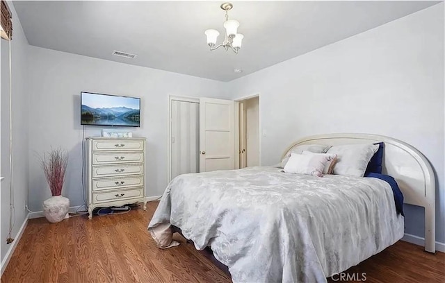 bedroom with dark hardwood / wood-style flooring and an inviting chandelier