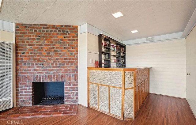 bar with a brick fireplace and hardwood / wood-style flooring