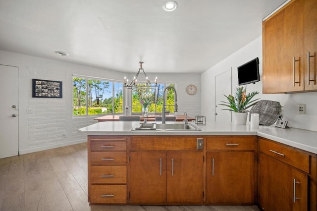 kitchen with sink, light hardwood / wood-style flooring, hanging light fixtures, and a notable chandelier