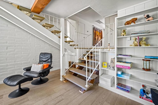 stairs featuring brick wall and hardwood / wood-style floors