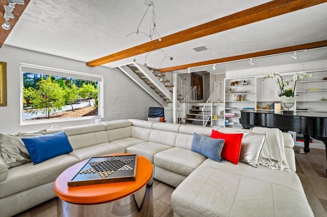 living room featuring brick wall, wood-type flooring, and beamed ceiling