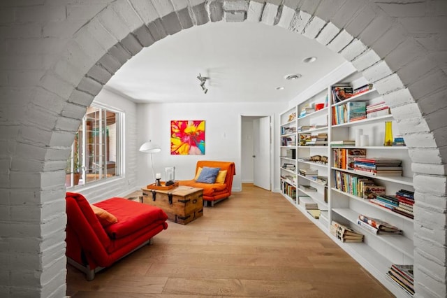 sitting room with built in shelves and hardwood / wood-style floors