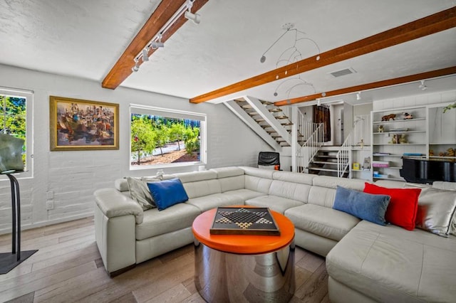 living room featuring beam ceiling, brick wall, and light hardwood / wood-style floors