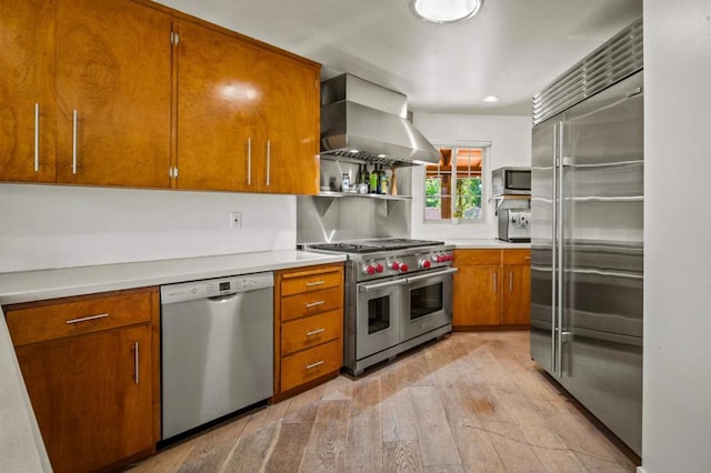 kitchen featuring tasteful backsplash, light hardwood / wood-style flooring, wall chimney exhaust hood, and high quality appliances