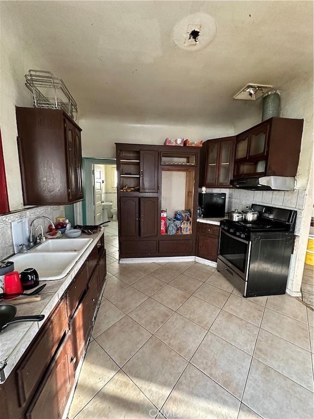 kitchen with black gas stove, light tile patterned floors, dark brown cabinets, and sink