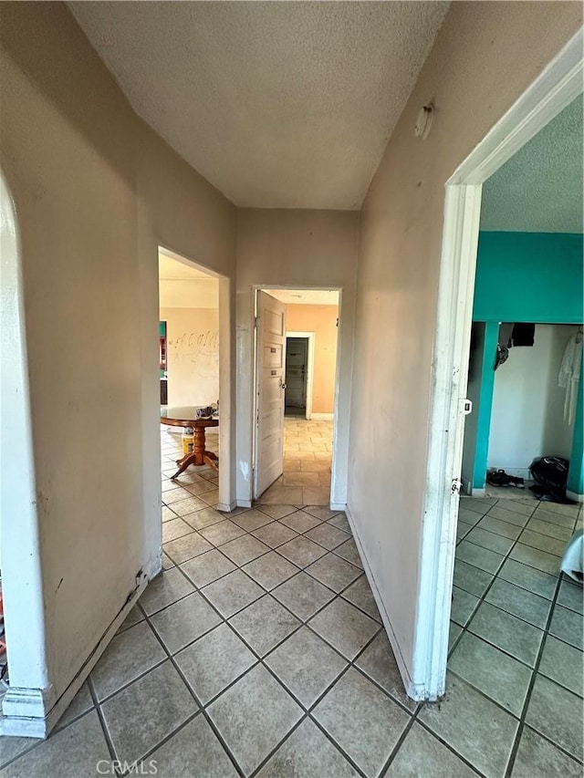 hall featuring light tile patterned floors and a textured ceiling