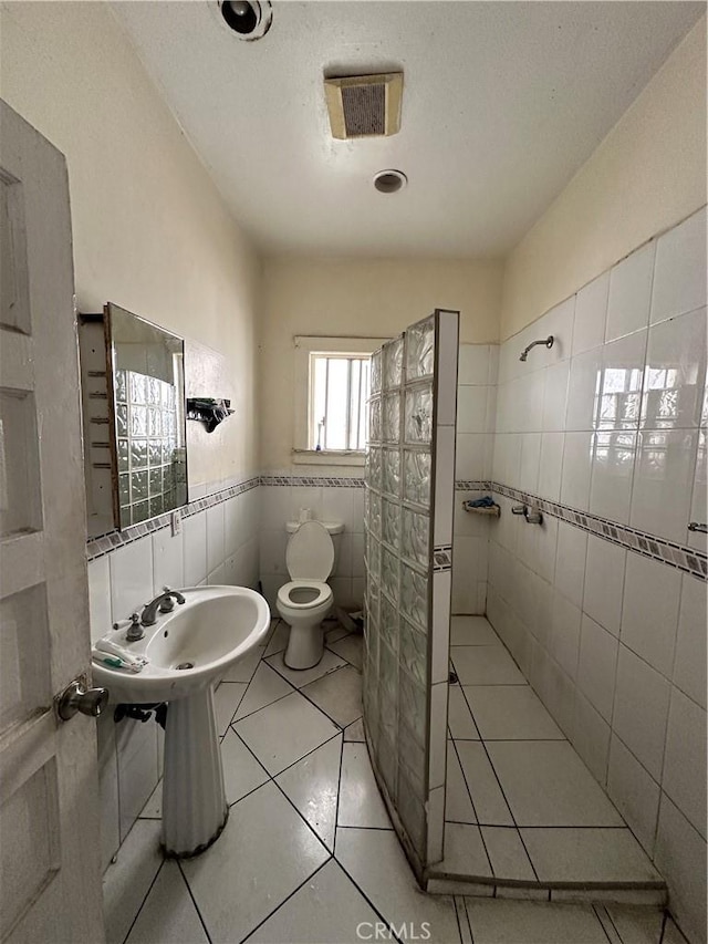 bathroom featuring tile patterned flooring, tile walls, and toilet