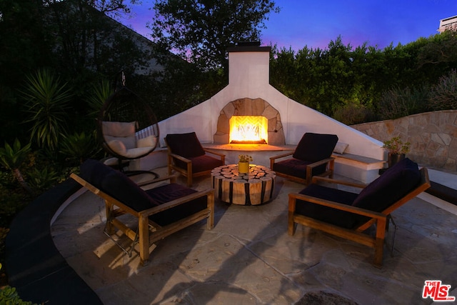 patio terrace at dusk with an outdoor fireplace