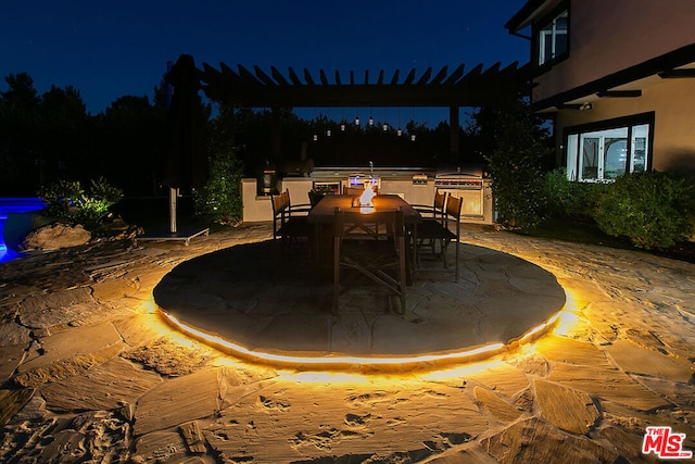 patio at twilight with area for grilling, grilling area, and a fire pit