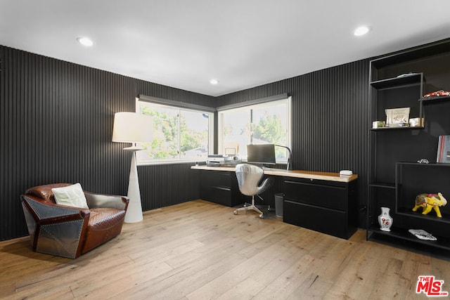 home office with built in desk and light hardwood / wood-style flooring