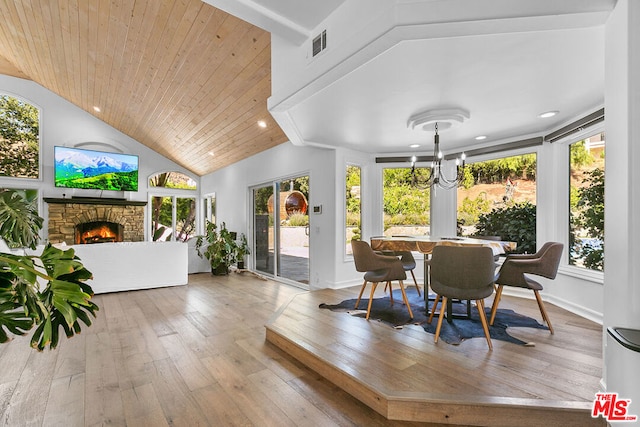 dining area with wooden ceiling, an inviting chandelier, lofted ceiling, a fireplace, and light wood-type flooring