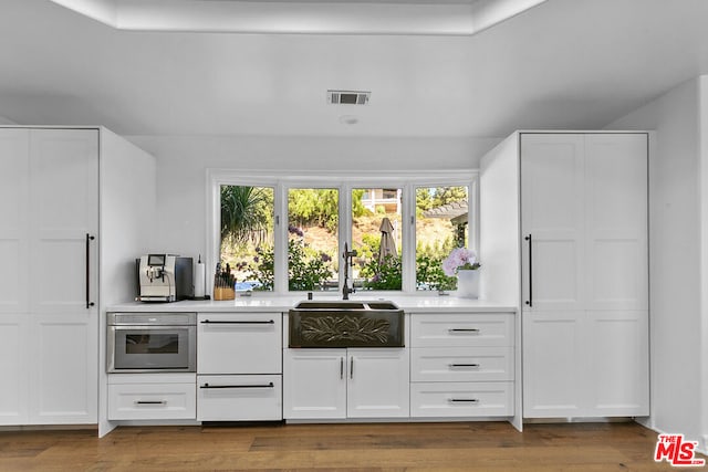 bar featuring white cabinetry, sink, and oven