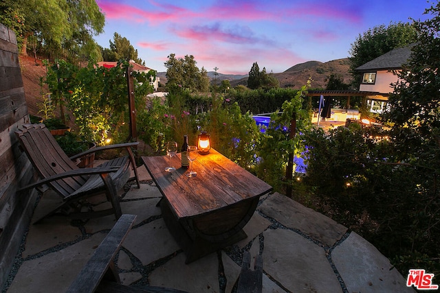 patio terrace at dusk featuring a pergola and a mountain view