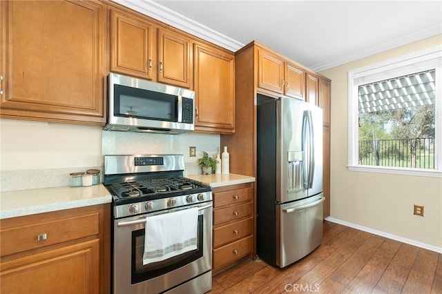 kitchen featuring appliances with stainless steel finishes, ornamental molding, and hardwood / wood-style flooring