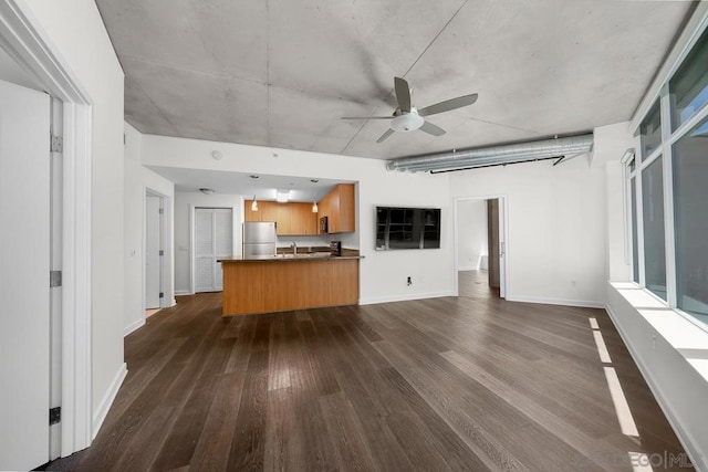 unfurnished living room featuring ceiling fan, dark wood-type flooring, and sink