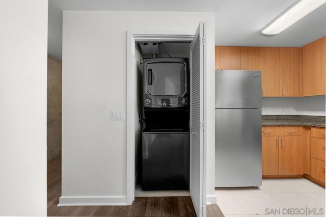 kitchen with light hardwood / wood-style flooring, stainless steel fridge, and stacked washer / drying machine