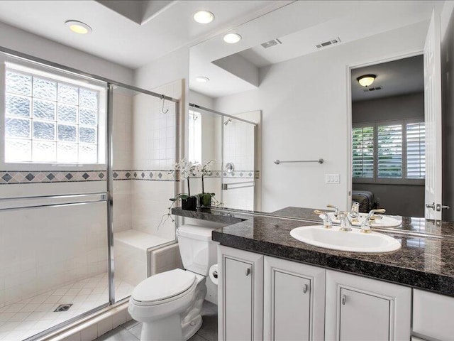 bathroom featuring tile patterned flooring, vanity, a shower with shower door, and toilet