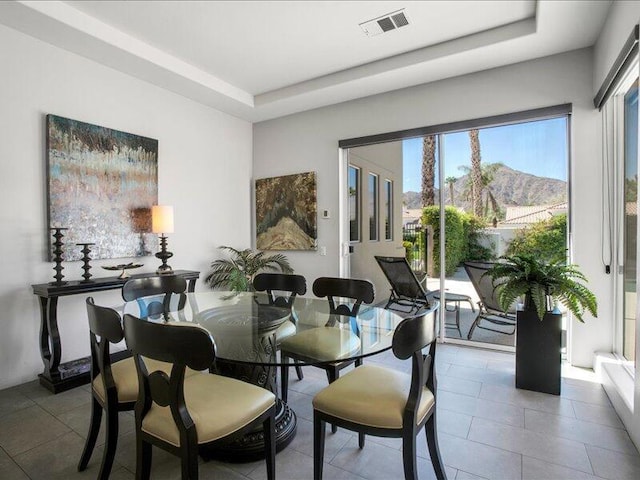 tiled dining area with a raised ceiling and a mountain view