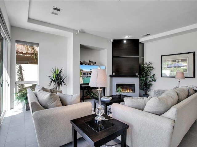 living room with a large fireplace and light tile patterned flooring