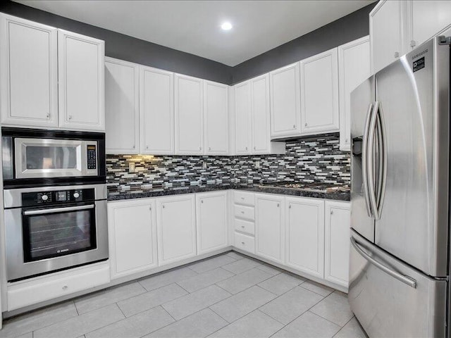 kitchen with white cabinets, tasteful backsplash, appliances with stainless steel finishes, and dark stone counters