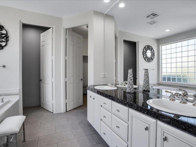 bathroom with tile patterned floors, tiled bath, and vanity