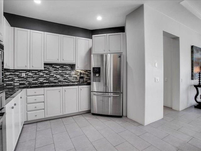 kitchen with stainless steel fridge, white cabinetry, backsplash, and light tile patterned floors