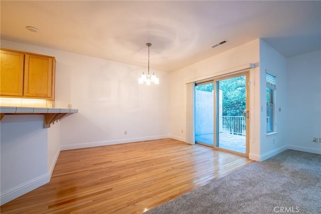 unfurnished dining area featuring light hardwood / wood-style floors and an inviting chandelier