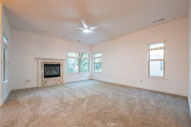 unfurnished living room featuring light carpet, a wealth of natural light, a fireplace, and ceiling fan