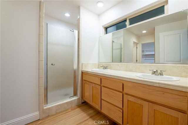 bathroom with wood-type flooring, vanity, a shower with shower door, and backsplash