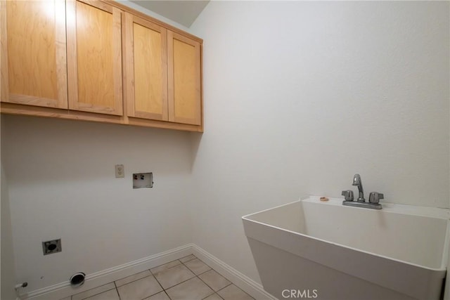 laundry area with electric dryer hookup, cabinets, light tile patterned floors, and sink