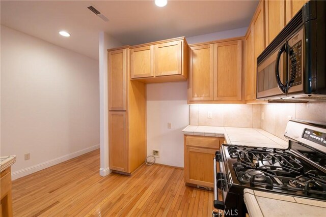 kitchen featuring range with gas stovetop, tile countertops, and light hardwood / wood-style flooring