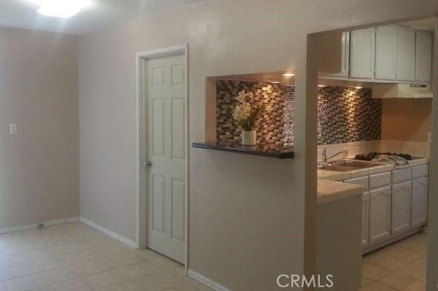 kitchen with sink, range hood, light tile patterned flooring, and gas stovetop