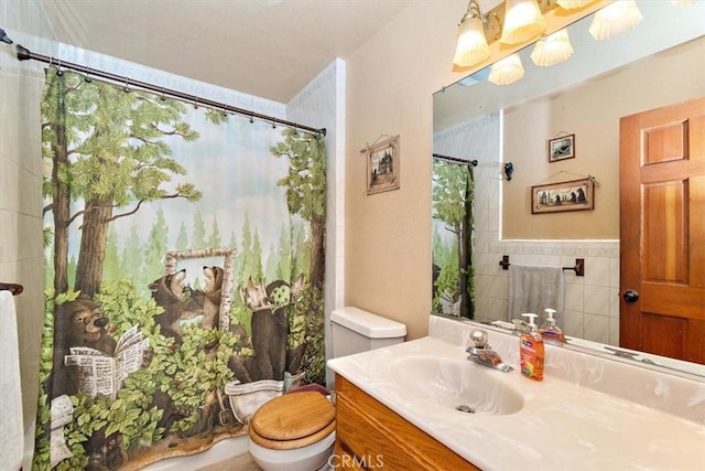 bathroom with tile walls, toilet, vanity, and a shower with shower curtain