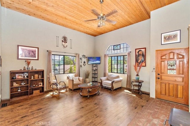 living area featuring ceiling fan, a high ceiling, hardwood / wood-style flooring, and wood ceiling