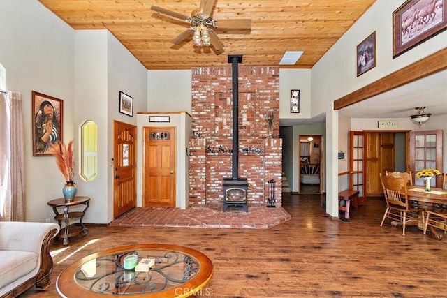 living room with a high ceiling, wood ceiling, a wood stove, and hardwood / wood-style flooring