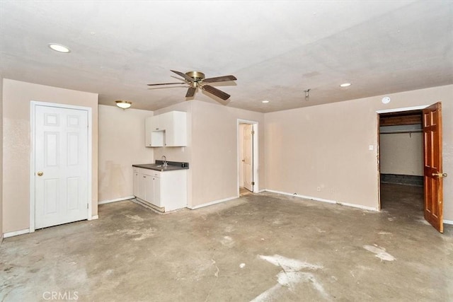 unfurnished living room with ceiling fan, sink, and concrete flooring