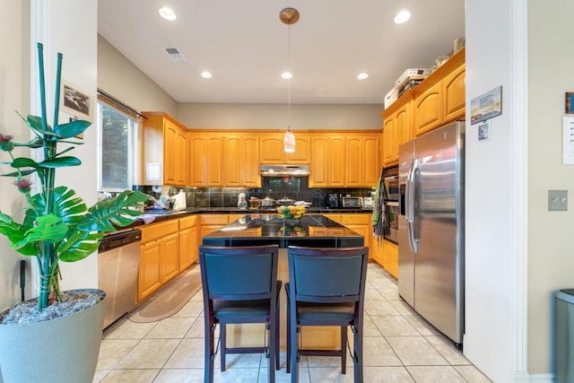 kitchen featuring decorative light fixtures, appliances with stainless steel finishes, light tile patterned floors, and a kitchen island