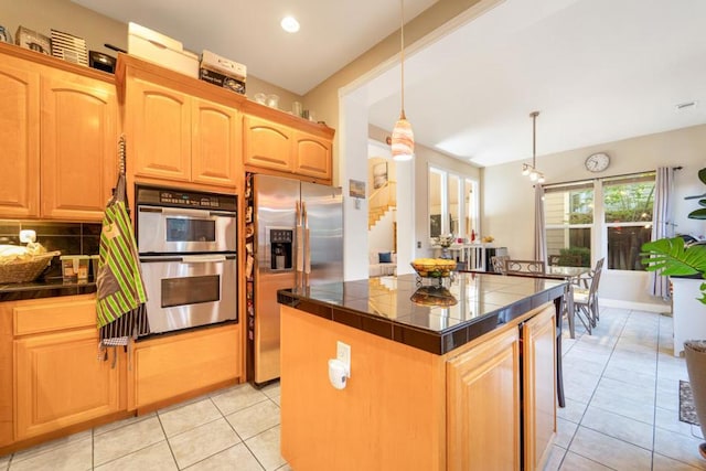 kitchen with decorative backsplash, a kitchen island, light tile patterned floors, stainless steel appliances, and decorative light fixtures