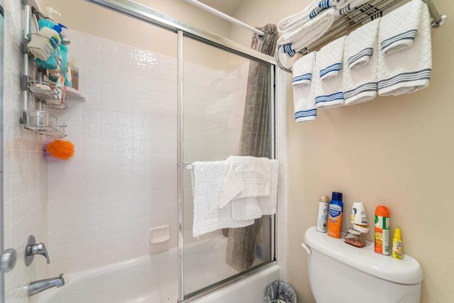 bathroom with bath / shower combo with glass door and toilet