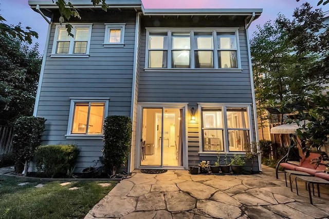 back house at dusk featuring a patio